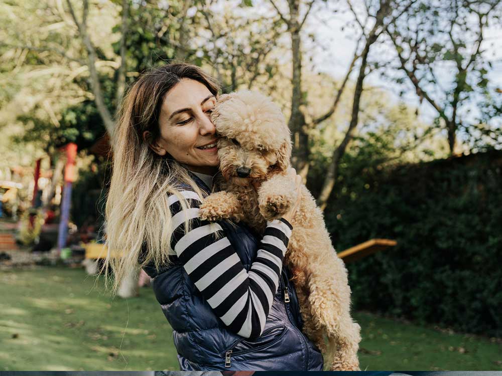 Woman-hugging-poodle-outdoors. Woman hugging poodle outdoors.